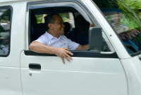 Bahlil tampak duduk di balik kemudi sebuah angkot putih tua, sebuah Suzuki Carry bernomor PB 7241 F. 