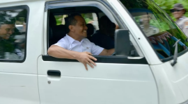 Bahlil tampak duduk di balik kemudi sebuah angkot putih tua, sebuah Suzuki Carry bernomor PB 7241 F. 