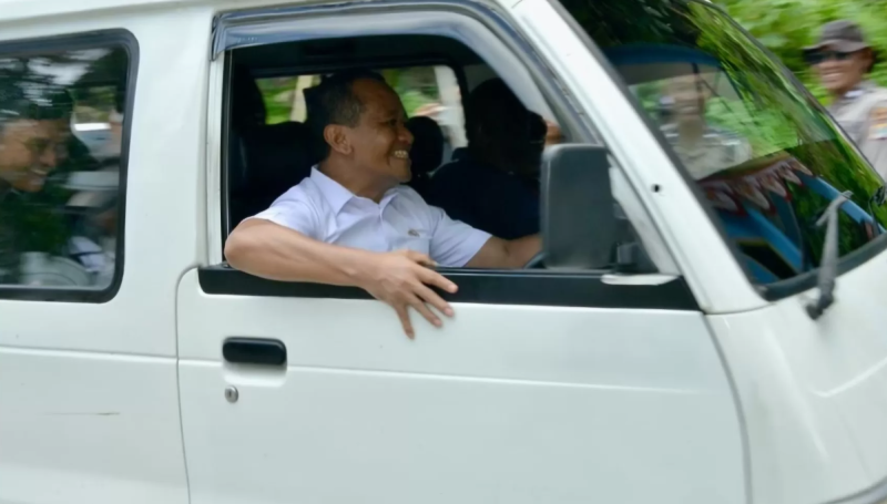 Bahlil tampak duduk di balik kemudi sebuah angkot putih tua, sebuah Suzuki Carry bernomor PB 7241 F. 