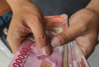 Asian man holding Indonesian Rupiah Money bills for giving, bribing, paying, counting concept.