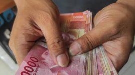 Asian man holding Indonesian Rupiah Money bills for giving, bribing, paying, counting concept.