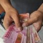 Asian man holding Indonesian Rupiah Money bills for giving, bribing, paying, counting concept.